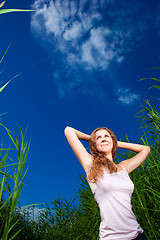 Image showing beautiful girl in pink among high green grass of summer meadow