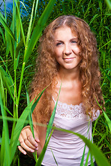 Image showing beautiful girl in pink among high green grass of summer meadow