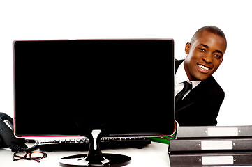 Image showing Businessman peeping from behind lcd monitor