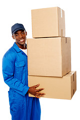 Image showing Young delivery guy holding stack of parcel boxes