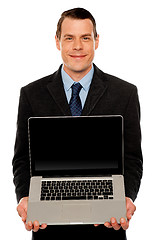 Image showing Smart businessman displaying laptop to you