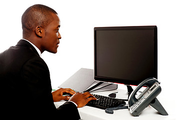 Image showing Male executive typing and looking at lcd screen