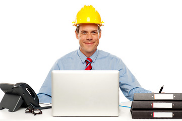 Image showing Architect wearing safety hat and using laptop