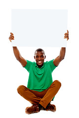 Image showing Seated young man holding white blank banner