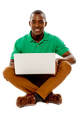 Image showing Cool guy seated on floor using laptop