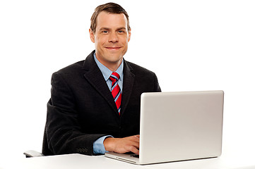 Image showing Male executive at work desk operating laptop