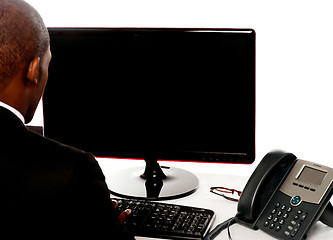 Image showing Rear view of male executive working on pc