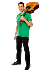 Image showing Casual music lover carrying guitar on his shoulders