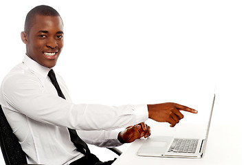 Image showing Smiling young african indicating on laptop screen