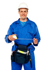 Image showing Male worker stretching measuring tape