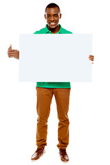 Image showing Casual young guy pointing towards placard