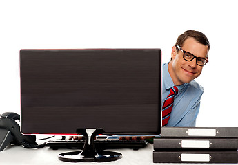 Image showing Man peeping from behind computer screen