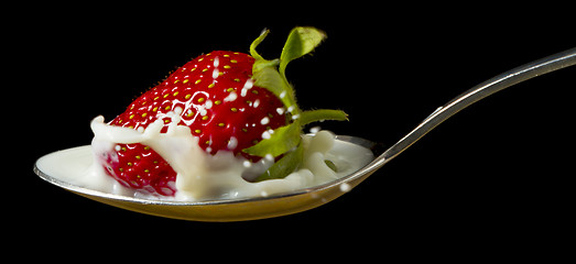 Image showing red, ripe strawberry falling in spoon with milk