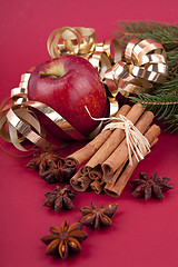 Image showing christmas decoration red apple, cinnamon, anise and tree on red background