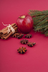 Image showing christmas decoration red apple, cinnamon, anise and tree on red background