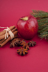 Image showing christmas decoration red apple, cinnamon, anise and tree on red background