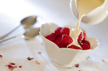 Image showing Cream Pouring From a Jug Over Fresh Raspberries