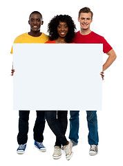 Image showing Smiling teenagers presenting blank billboard