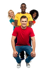 Image showing Young people standing behind semi seated guy