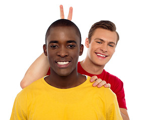 Image showing Guy making funny gesture behind his friends head