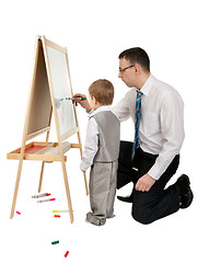 Image showing Businessman teaches his son to paint on an easel