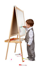 Image showing A child paints on an easel in the studio