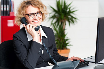 Image showing Front desk lady attending clients call