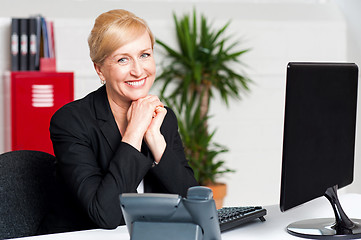 Image showing Aged businesswoman sitting with hands on chin