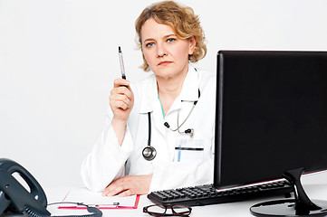 Image showing Serious aged doctor posing with pen in hand