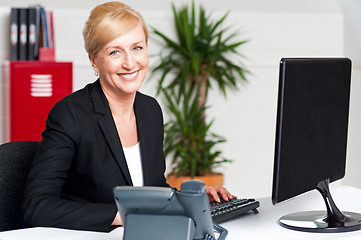 Image showing Smiling corporate woman typing on keyboard