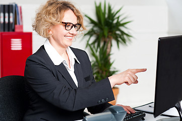 Image showing Cheerful woman pointing at computer screen