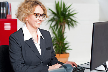 Image showing Aged woman in eyeglasses working on computer