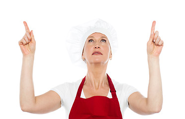 Image showing Female chef in uniform pointing upwards