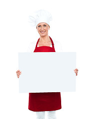 Image showing Happy female chef displaying white billboard