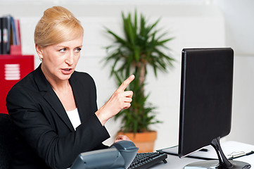 Image showing Angry woman indicating at computer led screen