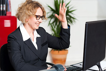 Image showing Smiling woman with raised arm looking at screen