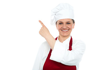 Image showing Aged woman chef pointing at copy space area