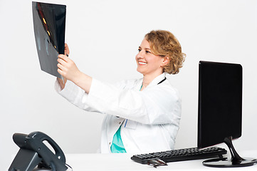 Image showing Smiling female surgeon looking at patients x-ray