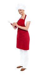 Image showing Pretty female cook writing recipe on notepad