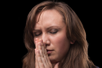 Image showing Young woman is in praying against dark background