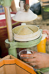 Image showing worker squeezing fresh orange juice old fashioned juice press ma