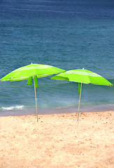 Image showing Two green sun umbrellas on the beach 