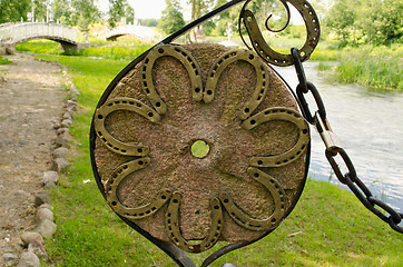 Image showing Horse shoes on old millstone and chain in park 