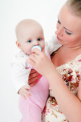 Image showing baby with a pacifier in the arms of mother