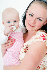 Image showing baby with a pacifier in the arms of mother