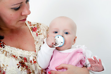 Image showing baby with a pacifier in the arms of mother