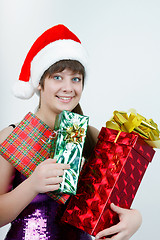 Image showing attractive girl in a Christmas hat with gift boxes