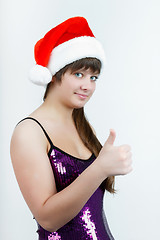 Image showing attractive girl in a Christmas hat with thumb up