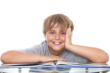 Image showing Smiling boy with  book on the table