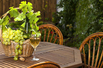 Image showing White wine bottle and bunch of grapes on basket, glass with in s